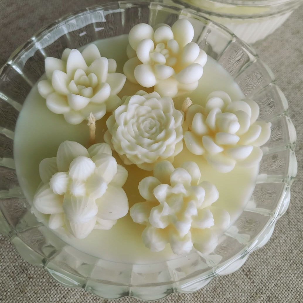 Vela aromática em frasco, feita em cera 100% vegetal e pavio de algodão. A vela possui 6 pequenas suculentas em cera e dois pavios, em pote de vidro decorado.