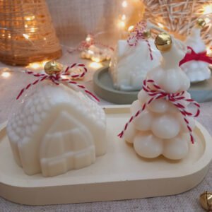 Casinha + árvore natalina em cera vegetal, com pavio de algodão e adorno festivo — acompanhadas de uma bandeja em ecomármore para completar a composição.